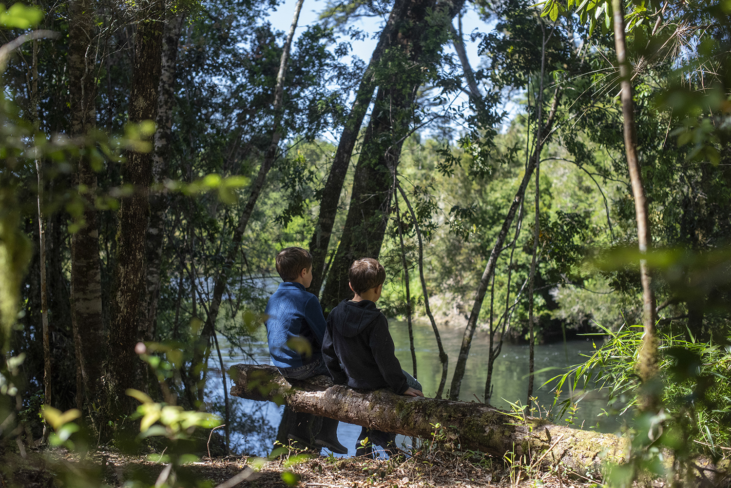 Niños sentados a la orilla del rio Parque Huillín